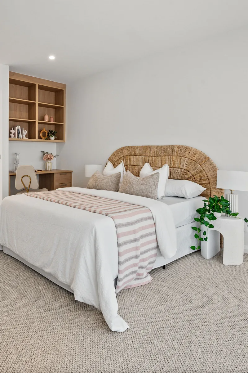 A guest bedroom styled with a rattan bedhead and layered white bedding.