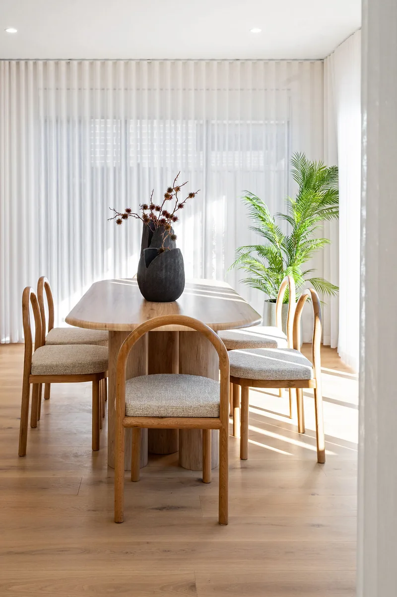 A dining setting styled with timber chairs and a sculptural vase.