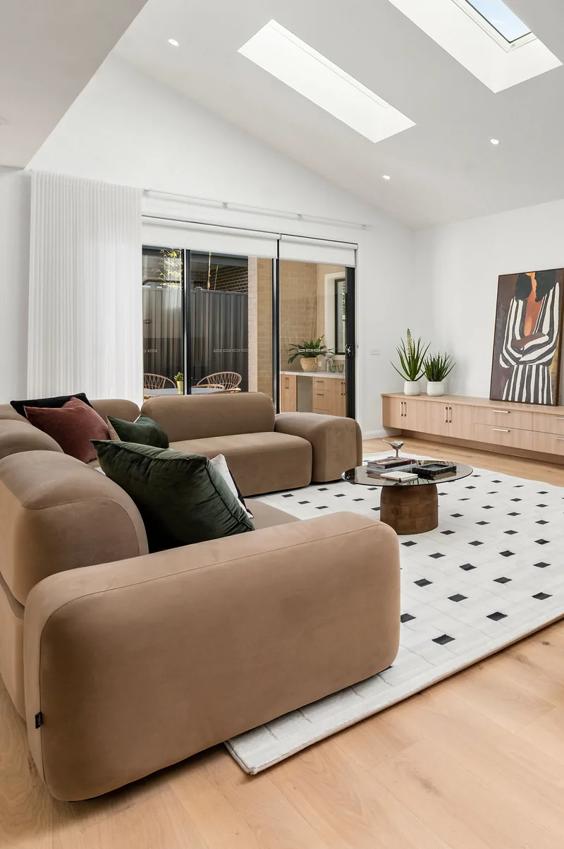 An open living space styled with tan sofas and a patterned rug.